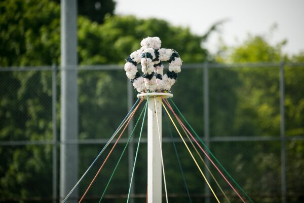 The top of a May Pole decorated with a crown of flowers