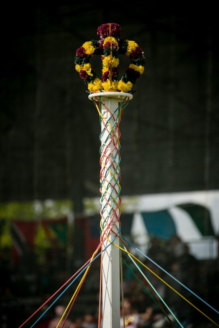 A May Pole, with a crown on the top, wrapped in cosingle lourful ribbons